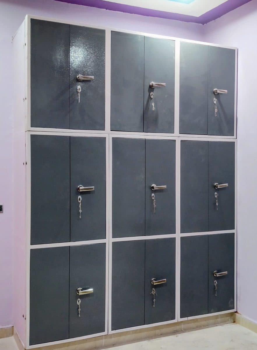 ईंट की दीवार वाली अलमारी पर लगे 9 ग्रे स्टील गेट, सफ़ेद फ्रेम और ताले के साथ